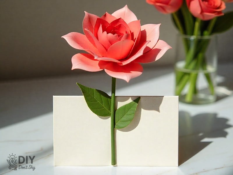 Paper flower with stem attached to front of handmade birthday card.