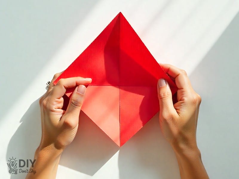 Folding the bottom corner of paper upward to form an envelope base.