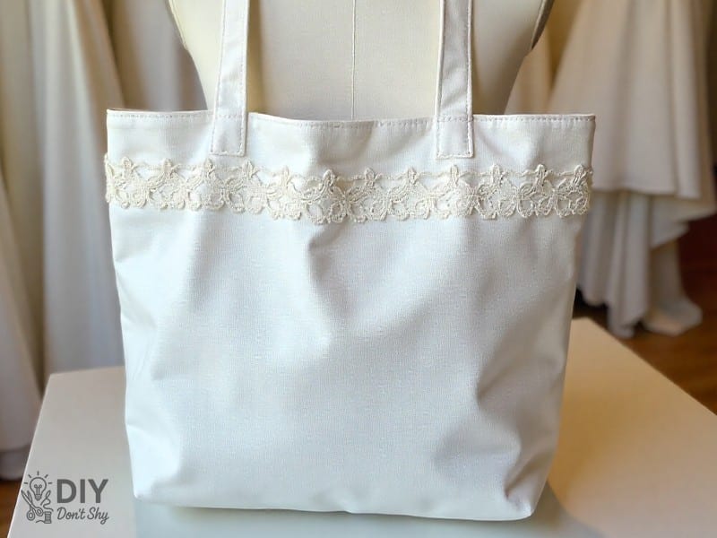 Attaching lining fabric to handmade tote bag with sewing machine.