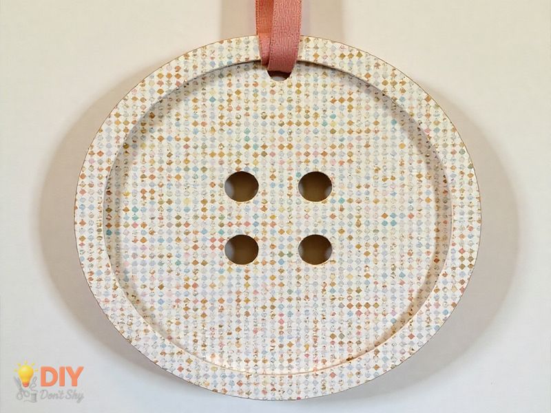 Large decorative paper button with ribbon, ready for wall display or party decoration.