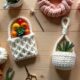 Handmade crochet gifts like coffee sleeve, plant hanger, and headband arranged with yarn and crochet tools on a wooden table.