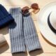 Handmade crochet gift ideas for men with beanie, sunglass case, wrist warmers, and cotton hat displayed on a wooden surface.