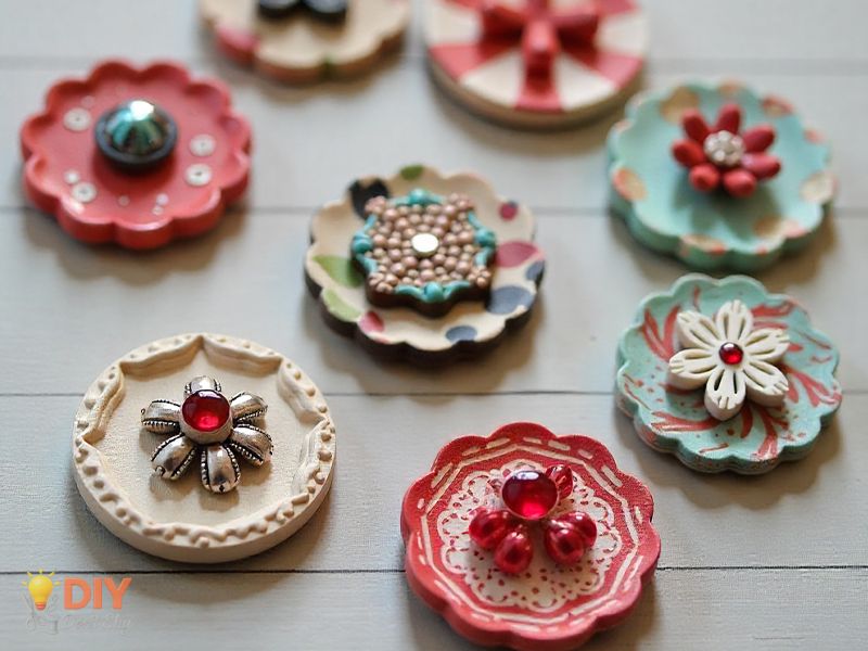 Decorated paper buttons with beads, sequins, and magnets displayed on a tabletop.