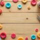 Handmade paper buttons on a craft table with scissors, patterned papers, and crafting tools.