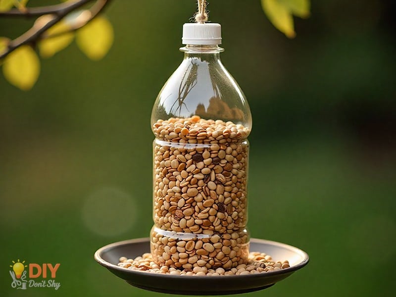 Plastic bottle bird feeder filled with seeds, hanging above a tray outdoors to catch falling seeds.