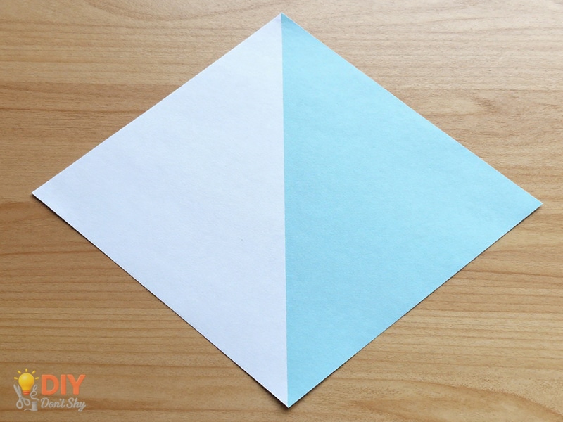 Diagonal fold of colored paper forming a triangle base for a glue-free paper flower