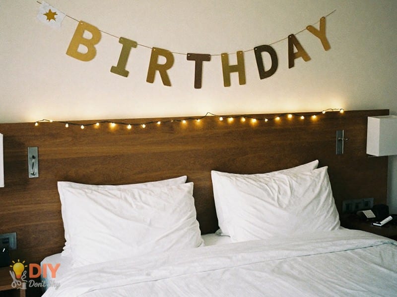 hang banners and lights first during a hotel room birthday decor process.