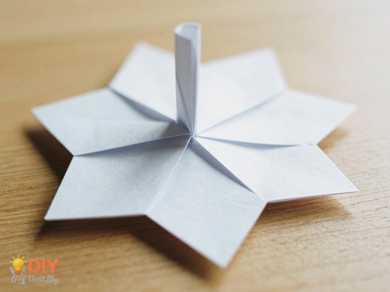 Final fold tucked under the base to secure a paper flower without glue